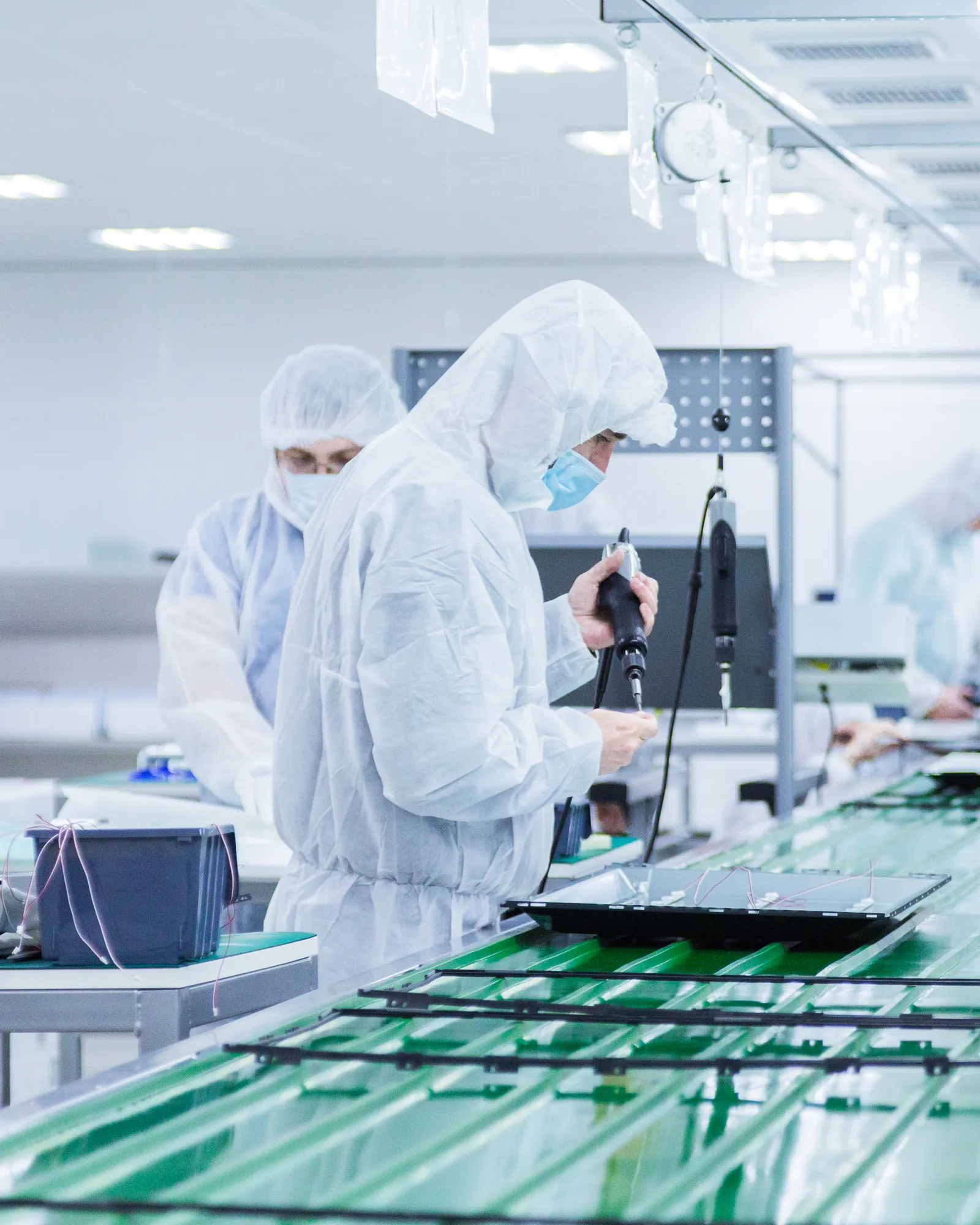 Technicians in cleanroom suits assembling components on an advanced manufacturing line